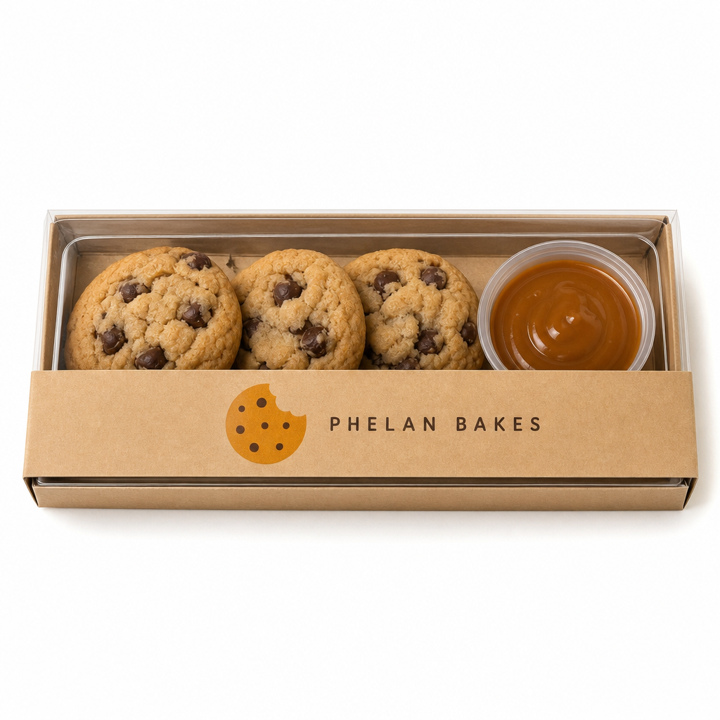 A Phelan Bakes kraft flight box with a clear lid, three mini cookies and a caramel dip cup