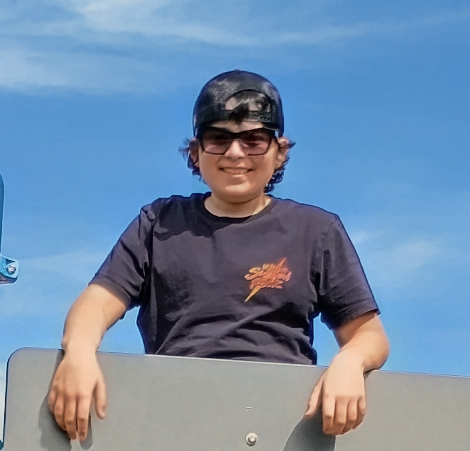 Owen Phelan, founder of Phelan Sips, smiling in a ball cap and sunglasses against a blue sky