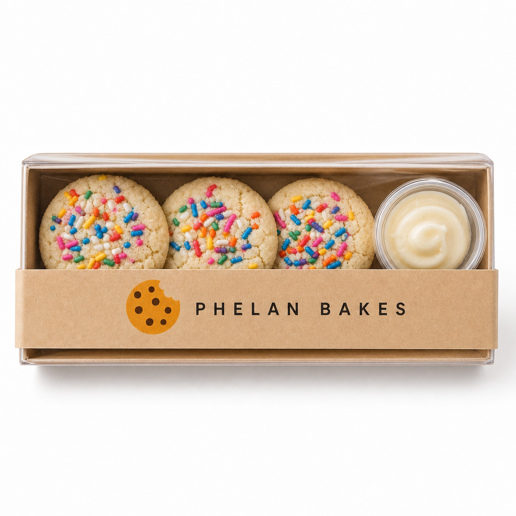 A Phelan Bakes kraft flight box with a clear lid, three sugar cookie minis and a vanilla icing dip cup